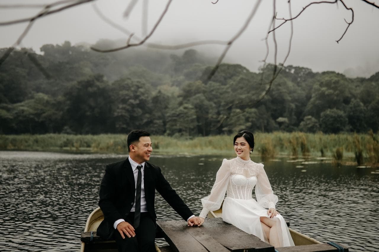 Bride and groom share a moment in a boat beside the water.