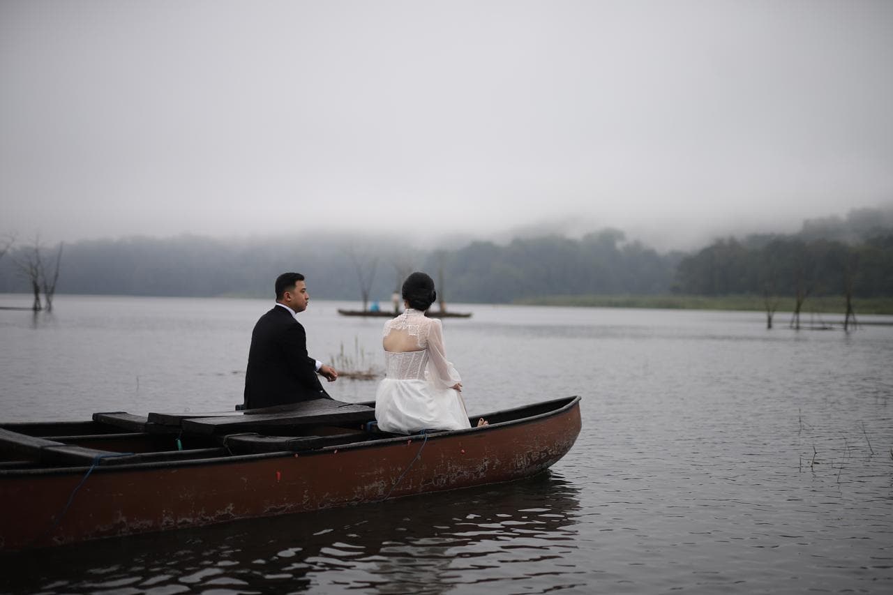 Bride and groom seated together in a boat.